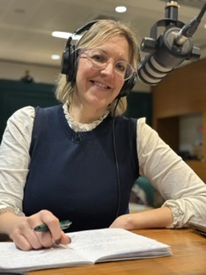 Dr Ellen Welch writing beside a microphone in a radio studio